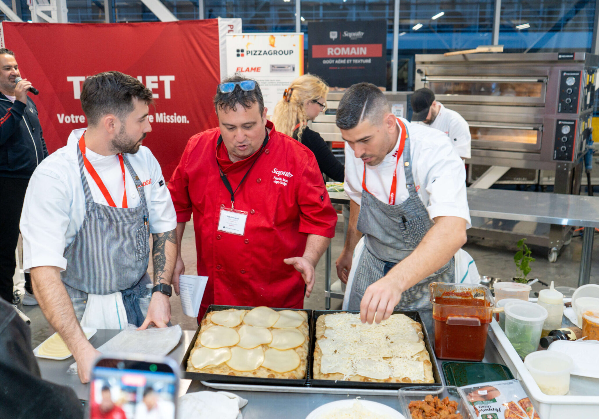 A judge speaking to competitors at the Gold Pizza Competition